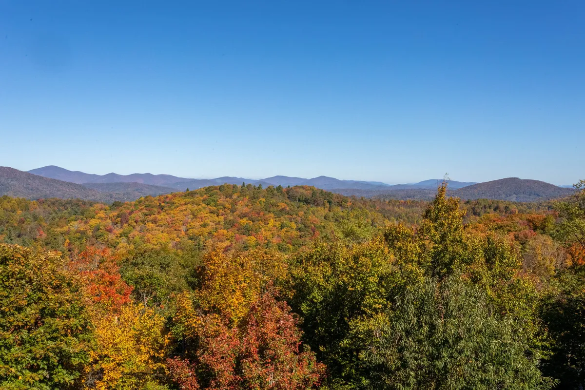 A breathtaking view of vibrant autumn foliage, rolling hills, and distant mountains, evoking the beauty and variety of the local landscape through all seasons. The colors and perspective make it easy to imagine hiking and exploring throughout the year.